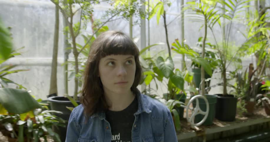 A woman walks through a greenhouse looking at plants