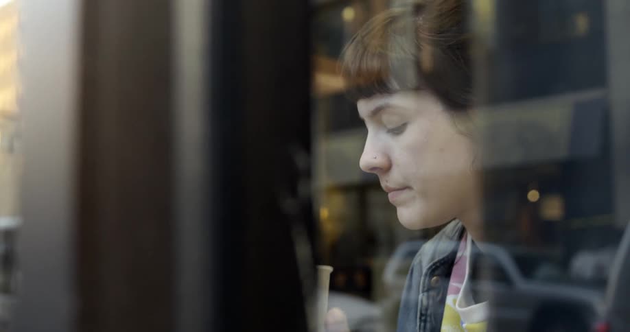 A woman is sitting in a store drinking from a cup