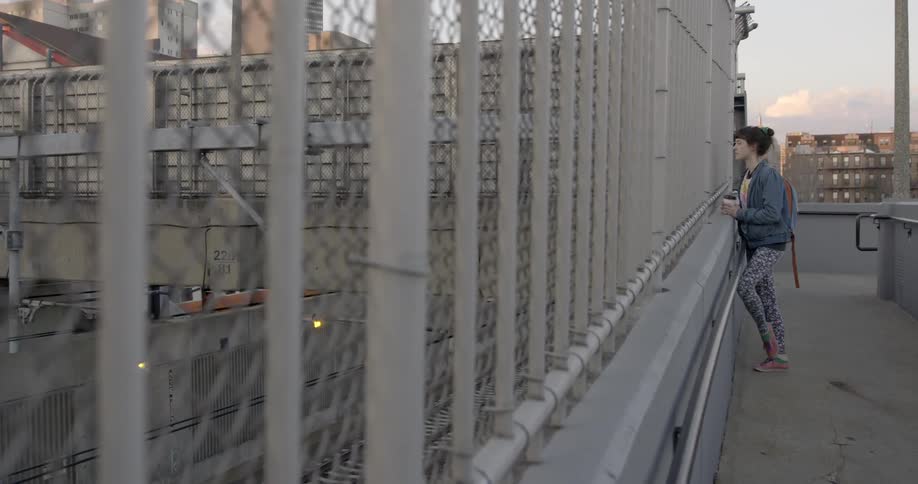 A person looks through a fence to the tracks below