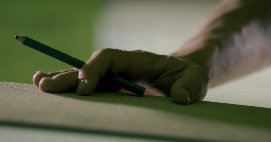 A man indoors holding a pencil