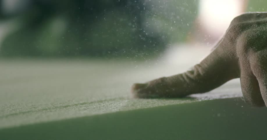 Man uses a sanding machine on the surface of a surfboard in a workshop