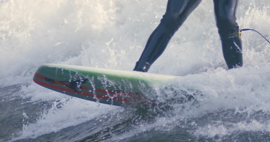 Person in skin tight suit with hook for board rides surfboard through splashing wave