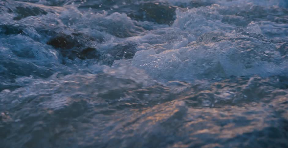 Water running over the rocks on a river at sunset