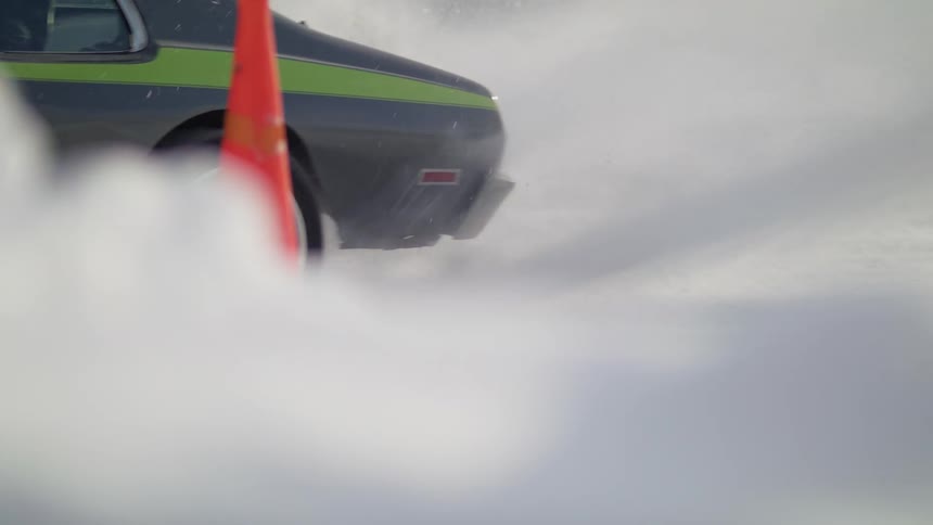Car wheels spin and snow flying behind the car as it drives off