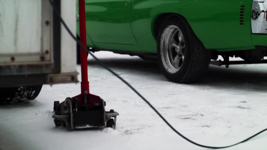 A person walks in front of a truck and car parked outside in the snow