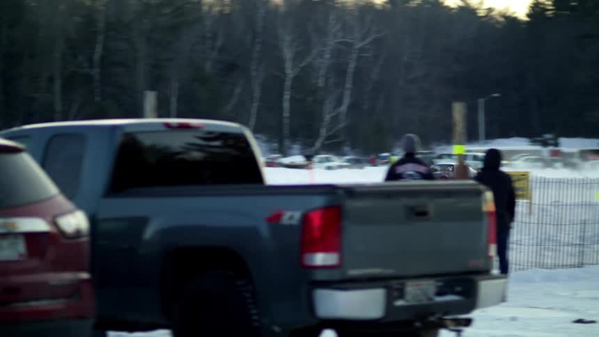 Vehicles race together on a race track in a snowy rural setting
