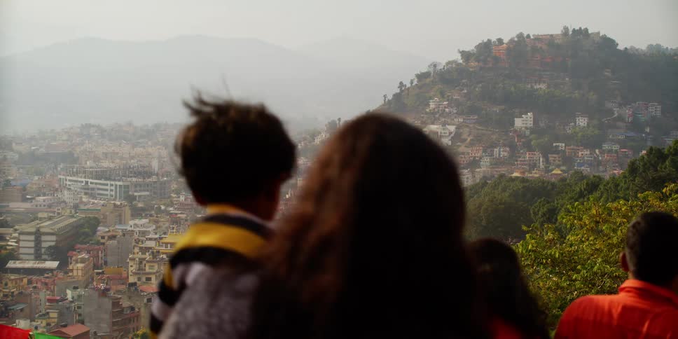 People walking down a hill with a city skyline in the background