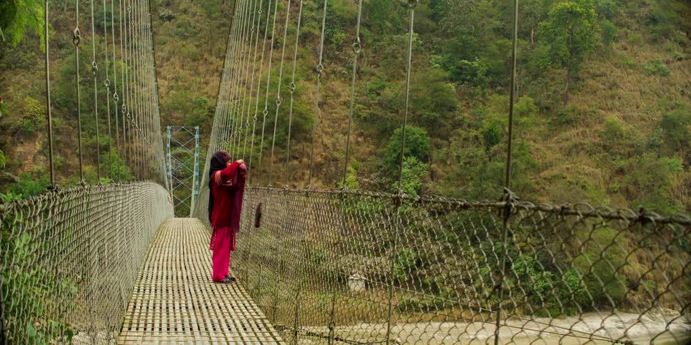 A girl hanging clothing over a bridge