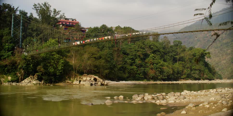 A house on a hill near a river and a mountain
