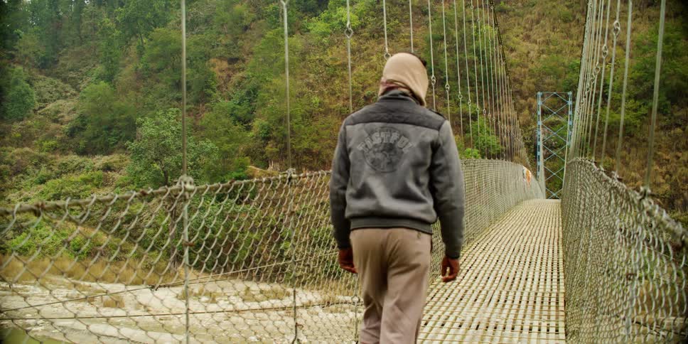 Two men walking across a suspension bridge
