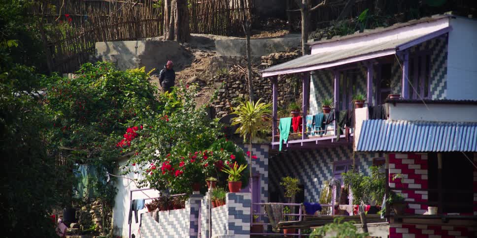 A man in a developing country walks down a hill in a neighborhood made of colorful houses