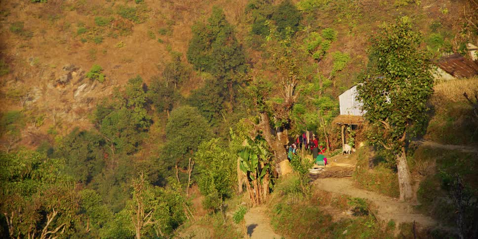 A woman in a rural area takes clothing off a clothes line outside