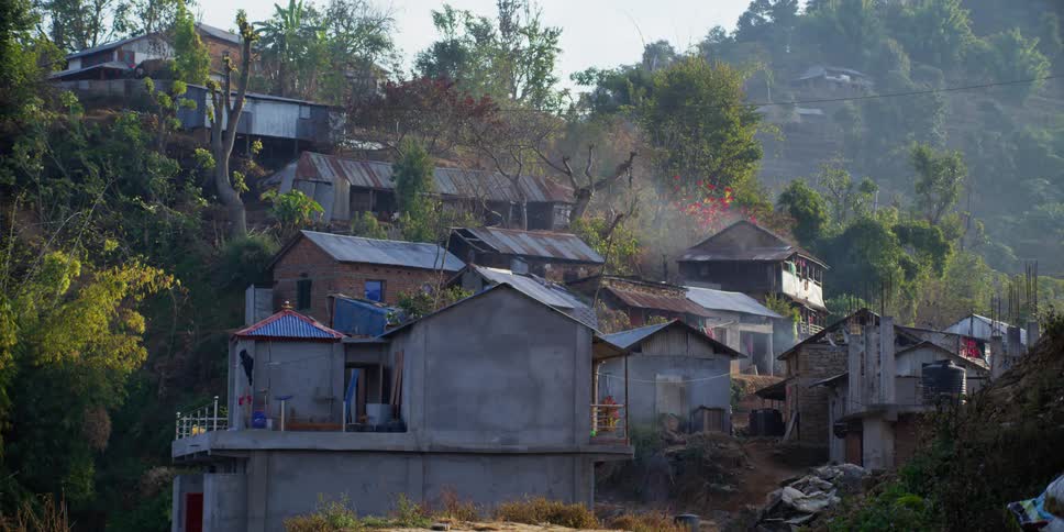 A person walking by housing in a primitive area