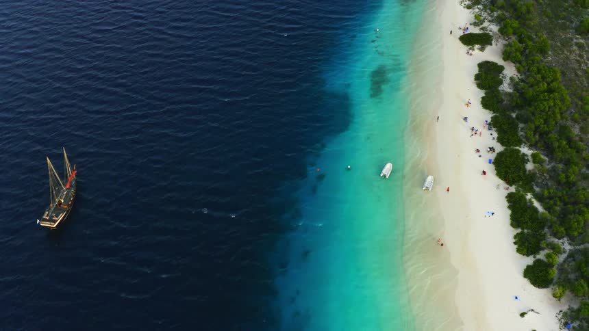 A birds eye view of a boat floating off a sandy beach