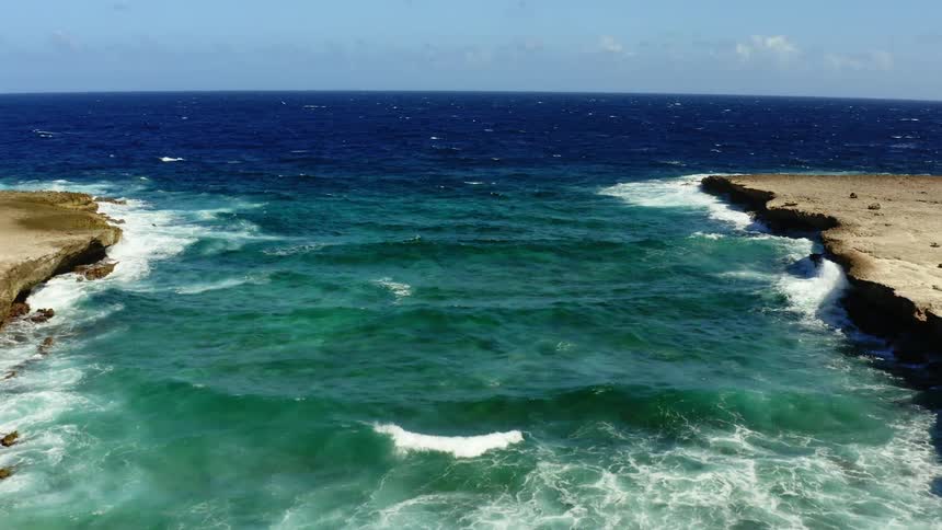 Turquoise ocean waves flowing towards a beach in the daytime