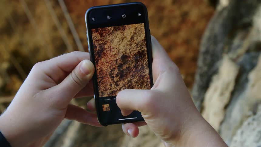 A person takes a picture of the dirt on the floor with a smartphone