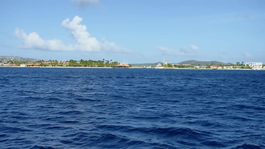 The deep blue ocean off the coast of a small city on a sunny day