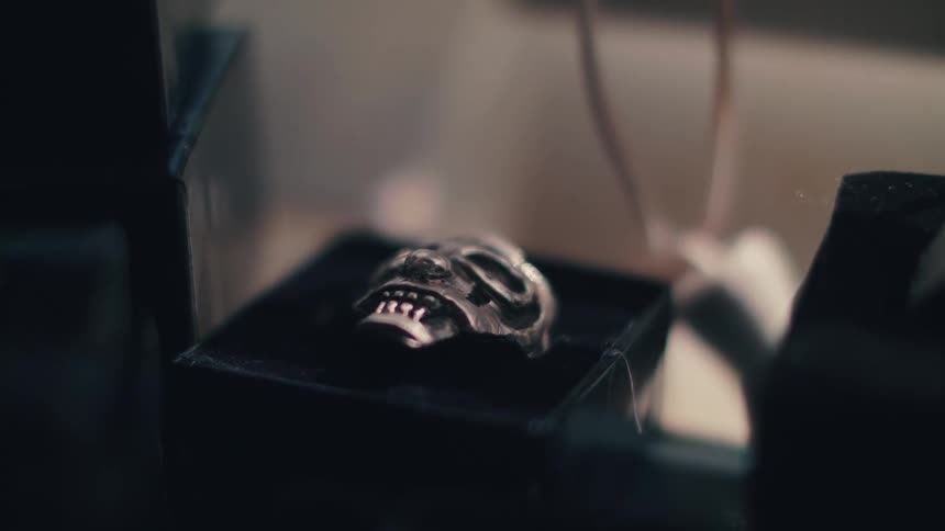 A silver ring shaped like a skull in a black box