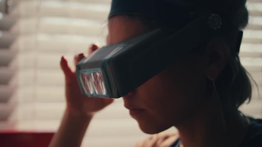 A female caucasian standing indoors wearing goggles and eyeglasses