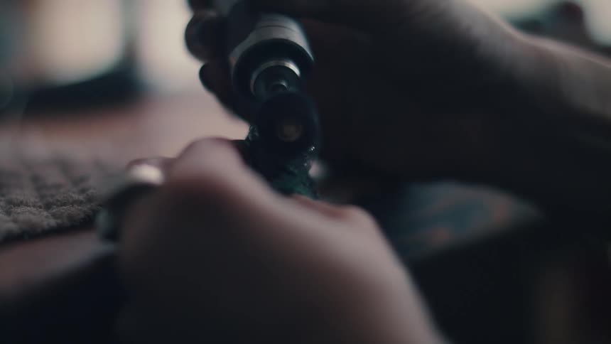 A person with a tool next to a table polishing a ring