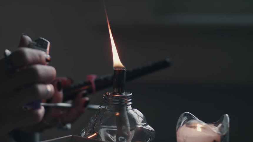 A woman lighting a glass torch and votive candle