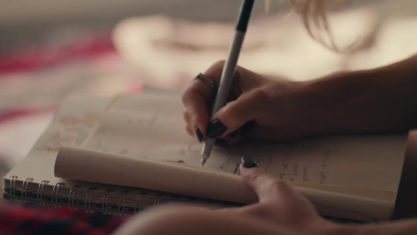 A teenage girl at home writing in a notebook