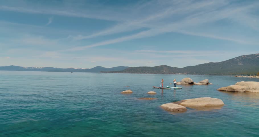 Two people on paddle boards paddling on the water