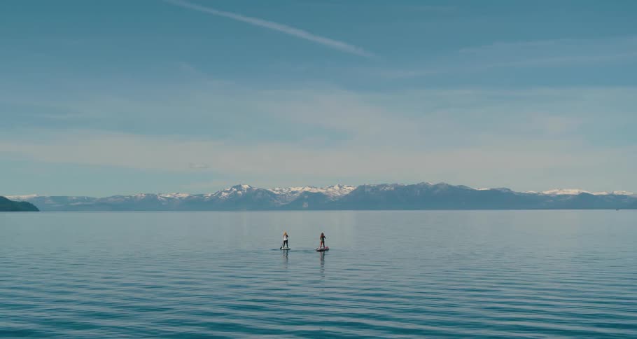 Two people on paddle boarding on a river
