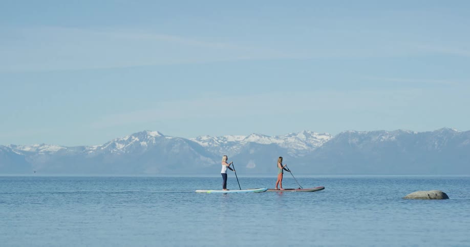 Two women paddle boarding on a lake