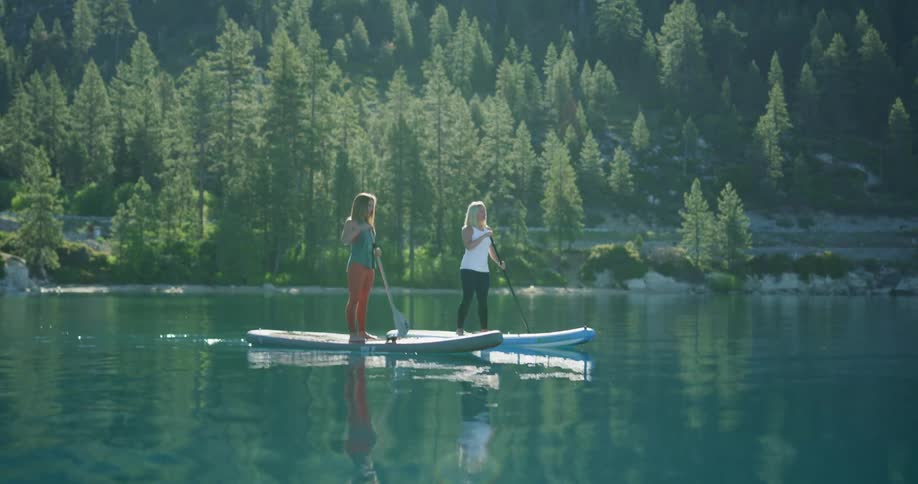Two women in a lake paddling on paddle boards