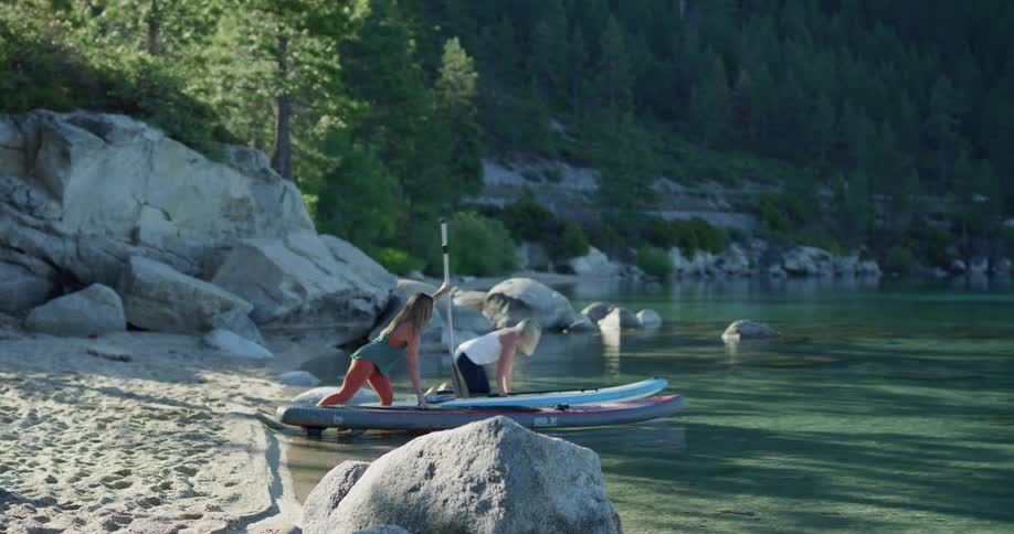 Two women put their paddle boards in the water and start paddling