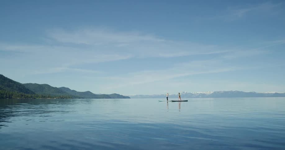 Two women paddle board towards shore