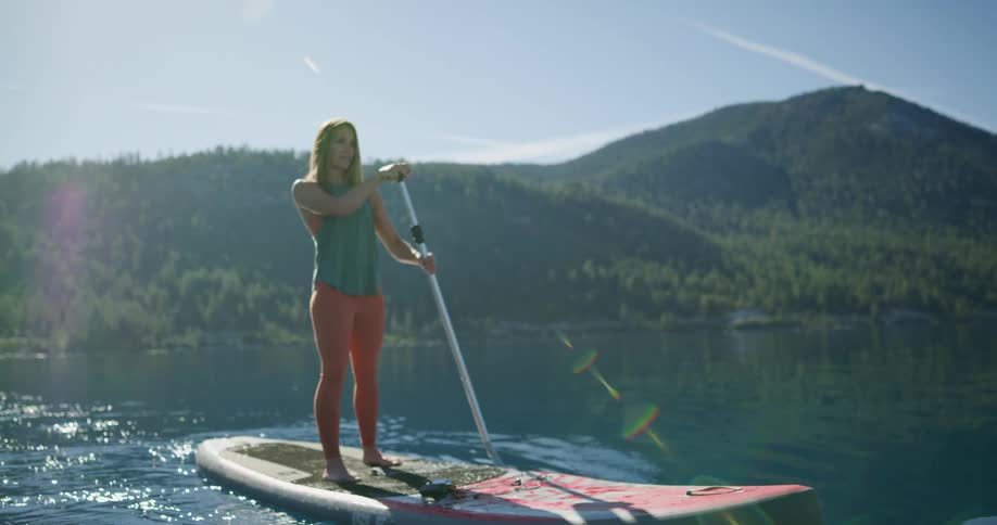 A female caucasian paddling on a river on a paddle board
