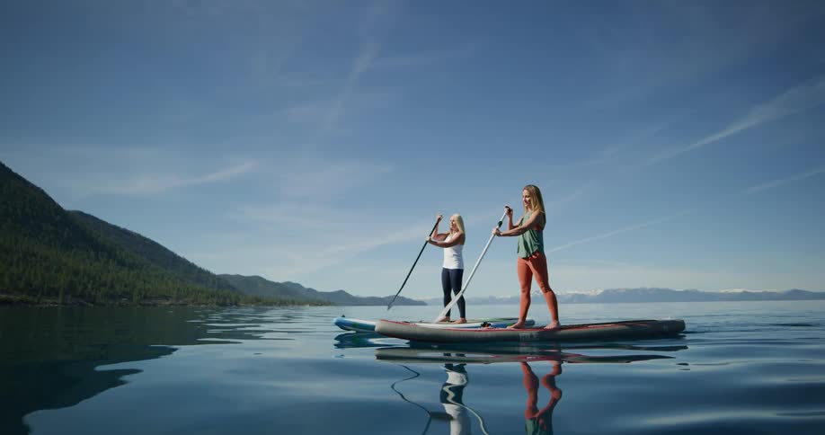Two women paddle boarding on a lake