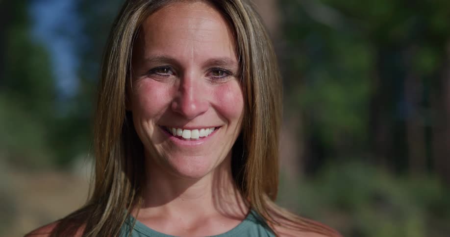 Woman with brown hair faces the camera smilingly with eye contact