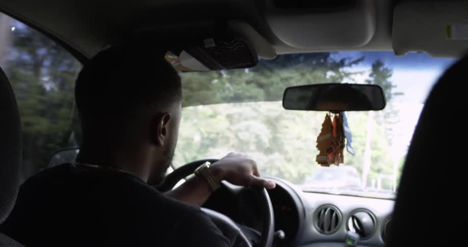 A man is driving a car on a sunny day