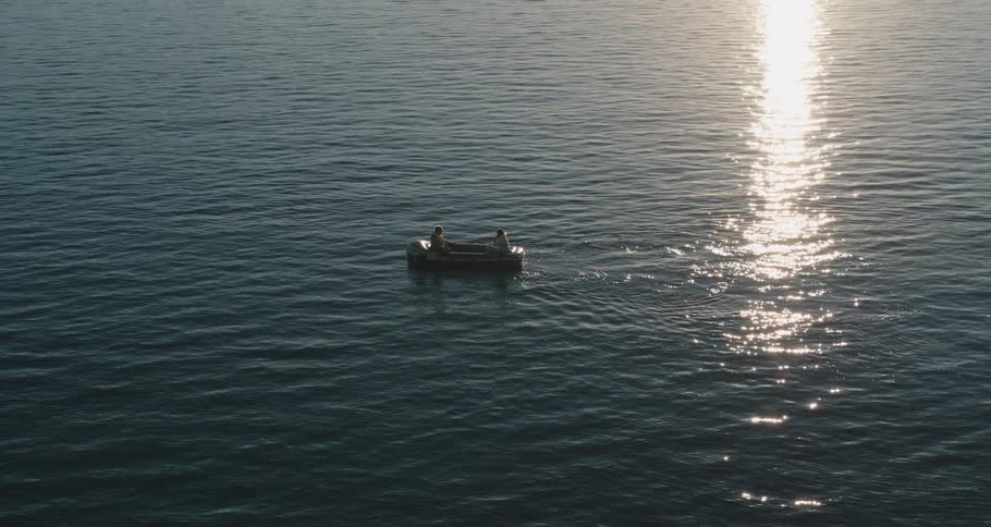 Two people are rowing a boat across a large body of water