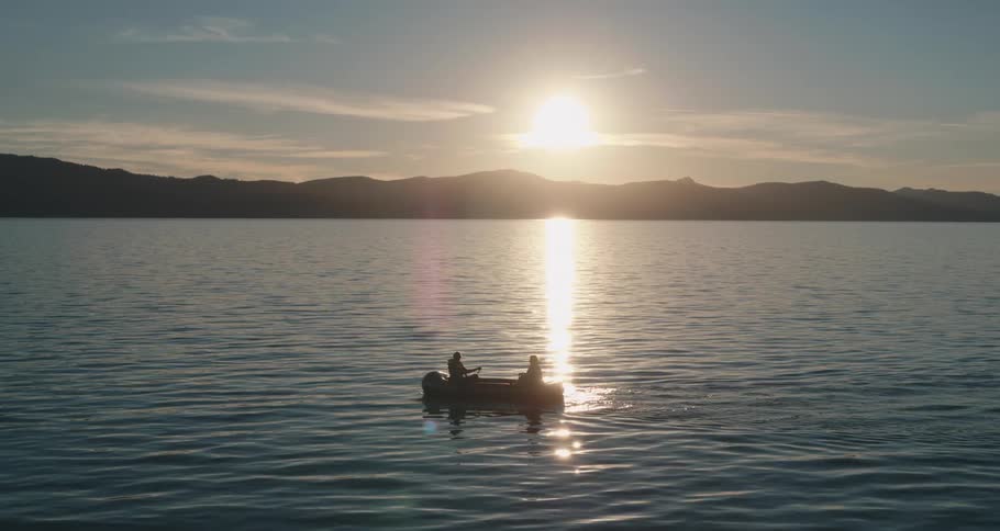 People row across water in rowboat crossing the suns reflected light