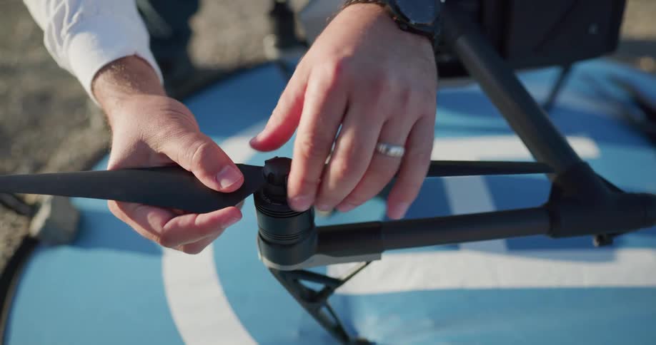 A man outside attached propellers to a drone