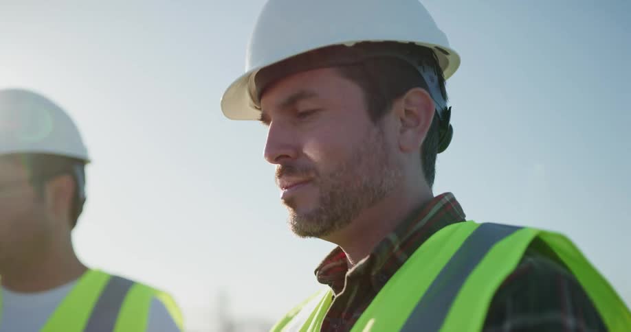 Construction worker wearing white hard hat and green vest in a construction site