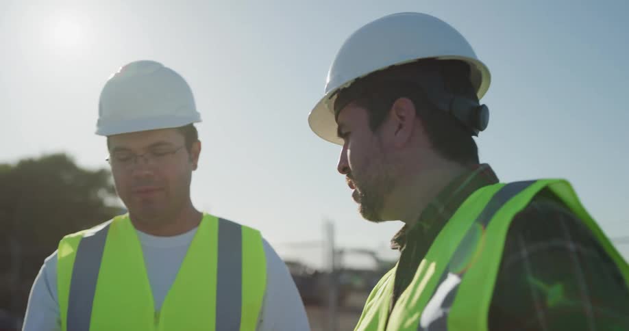 Two construction workers talk as they look at tablets