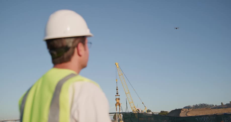 A construction worker flies a drone over a construction site