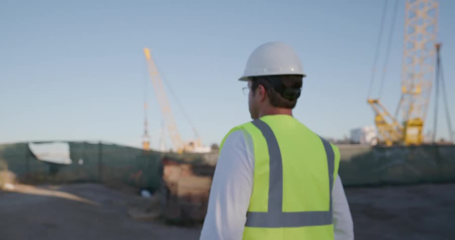 A male walking with a briefcase on a construction site