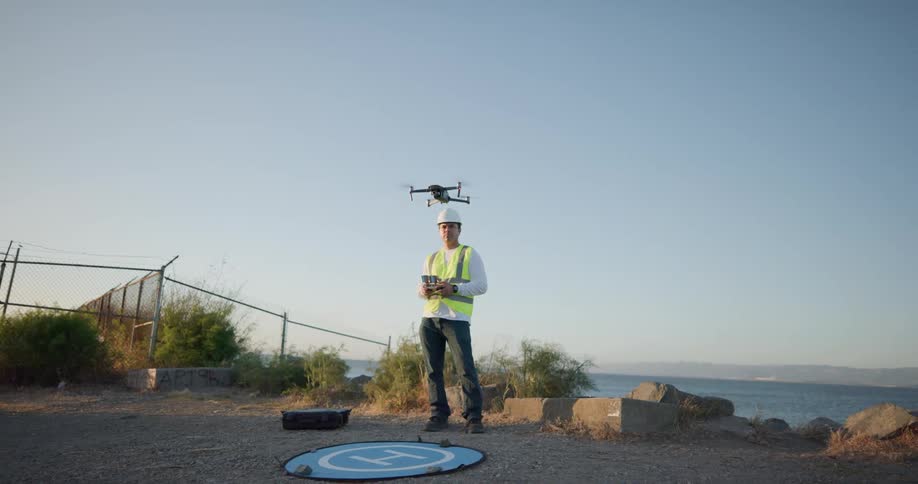 A construction worker standing outside operating a drone