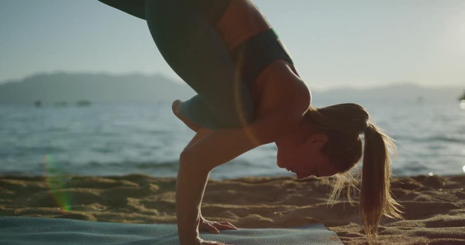 A woman does a handstand while practicing yoga on the beach