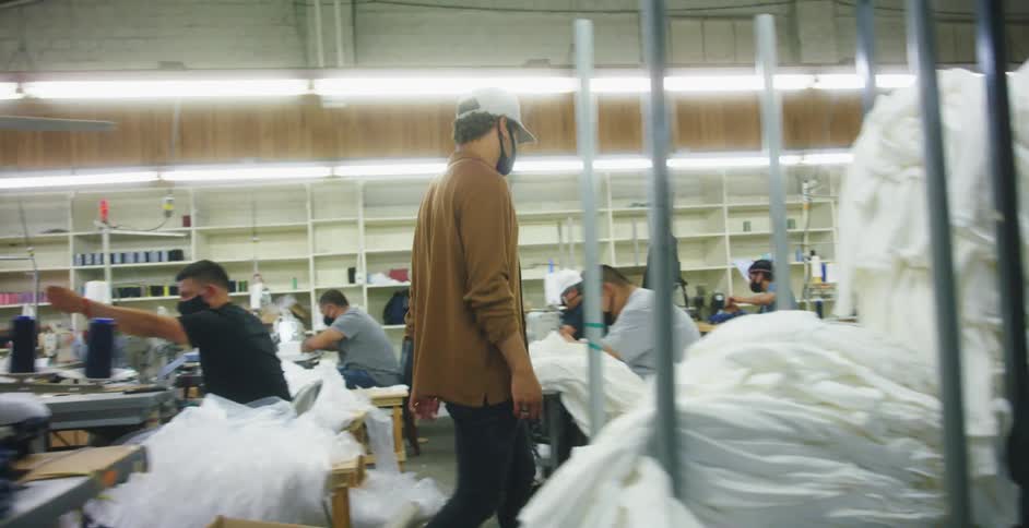 A man with a hat and mask walking in a textile factory