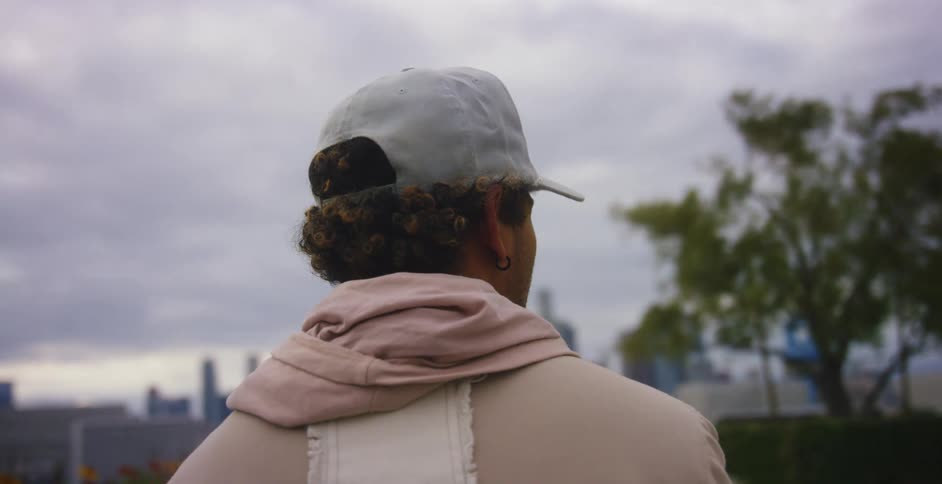 A man stands in a park with a city skyline off in the distance