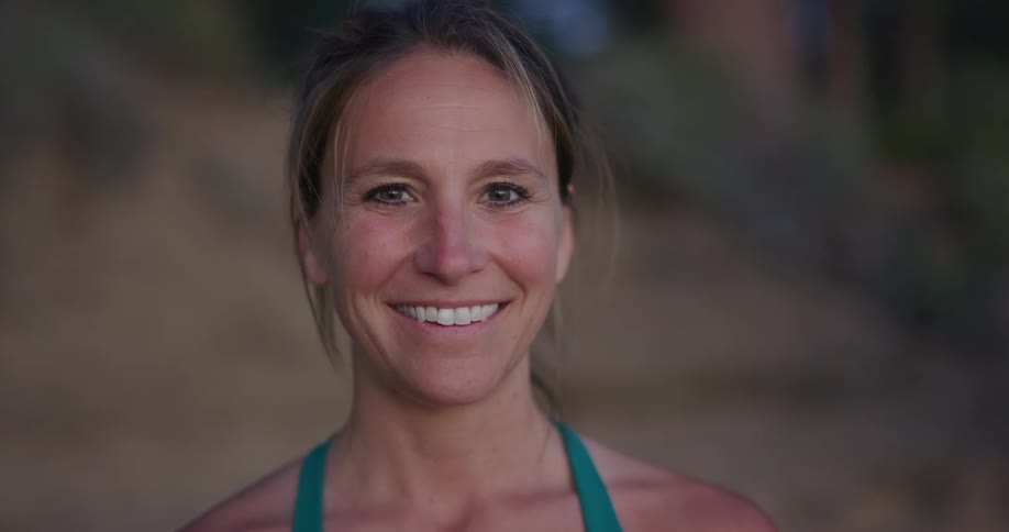 Middle aged blonde woman with a ponytail faces the camera smilingly with eye contact