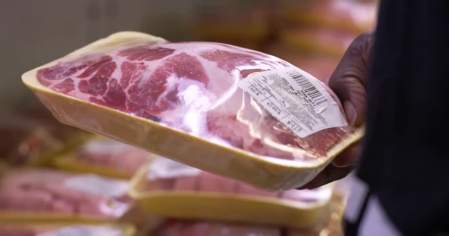 A man is examining meat in a market