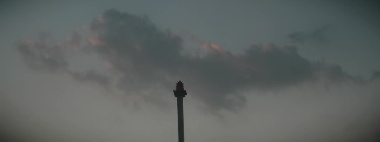 A pole with a light on it near the sky and clouds